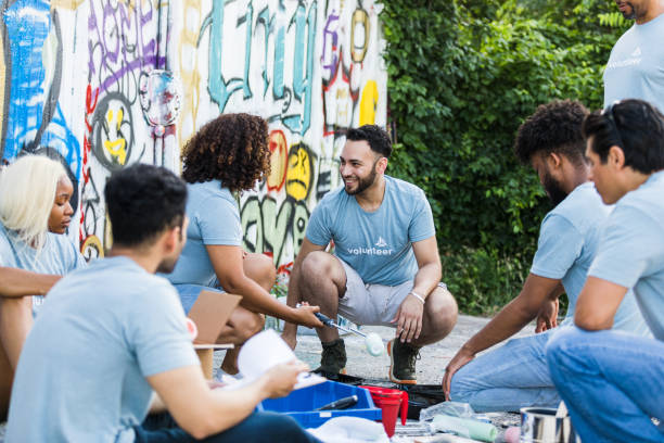 the group of volunteers take a break from painting the graffiti wall.